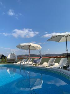 a swimming pool with chairs and umbrellas at Vila Impresija Fruska gora in Novi Sad