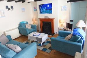 een woonkamer met 2 blauwe stoelen en een open haard bij Blue Cat Cottage in Penzance