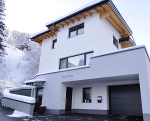 une maison blanche avec un garage dans la neige dans l'établissement Apart Holiday, à Kappl