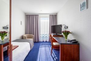 ジェロナ・グラにあるQubus Hotel Zielona Góraのベッド、デスク、テレビが備わるホテルルームです。