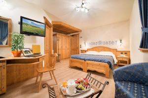 Cette chambre d'hôtel comprend une chambre avec un lit et une télévision. dans l'établissement Hotel Costanza Mountain Holiday, à Livigno