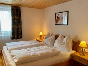 ein großes weißes Bett in einem Schlafzimmer mit zwei Lampen in der Unterkunft Am Romberg in Dornbirn