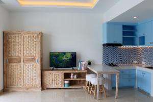 eine Küche mit blauen Schränken, einem Tisch und einem TV in der Unterkunft Ocean Star Apartment Sanur in Sanur