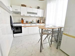 uma cozinha com armários brancos e uma mesa de madeira em Apartment Hroncová, near city centre and park, quiet location em Košice