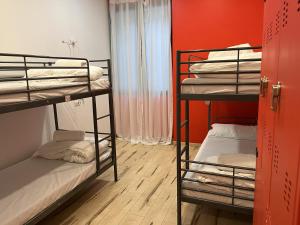 Cette chambre comprend 2 lits superposés et un mur rouge. dans l'établissement QUO Milano, à Milan