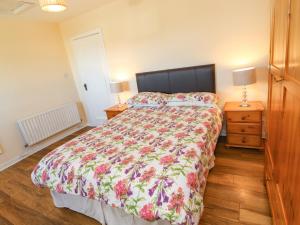 1 dormitorio con 1 cama grande con colcha de flores en Sea Park Cottage, en Lahinch