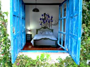 1 dormitorio con puertas azules y 1 cama en una habitación en Hotel Boutique Casa de Hacienda Su Merced, en Puembo