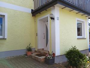a yellow house with a white door and plants at Ferienwohnung am Hopfenstodl in Illschwang