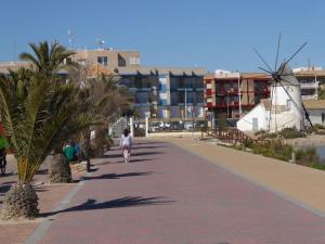 a person walking down a sidewalk with palm trees at Maison rénovée à 250m de la mer in Santiago de la Ribera