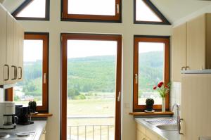 a kitchen with three windows and a view of a field at Ferienwohnung am Denkmal in Bad Berleburg +19 photos