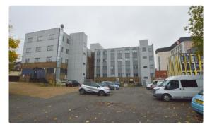 a parking lot with cars parked in front of buildings at Spacious modern flat in Luton town centre in Luton