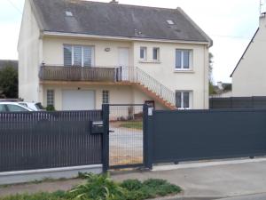 ein weißes Haus mit einem schwarzen Zaun und einem Tor in der Unterkunft Le mulon de Guérande in Guérande