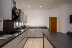 a kitchen with white cabinets and a black counter top at Casa Fresa - Seamen's Chapel in Dundee