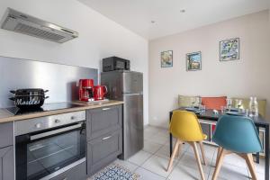 a kitchen with a stainless steel refrigerator and two chairs at Nid douillet pour 3 à 100m de la mer in La Plaine-sur-Mer +13 photos
