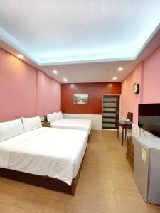 a bedroom with two beds and a flat screen tv at Yi-Shiou Home in Taitung City