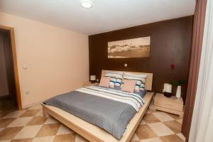 - une chambre avec un grand lit et une tête de lit marron dans l'établissement M&M Apartments, à Biograd na Moru
