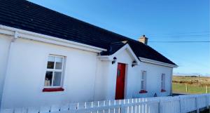 uma casa branca com uma porta vermelha e uma cerca em Be's Cottage em Malin Head