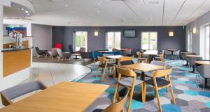 a restaurant with tables and chairs in a room at Holiday Inn Express Manchester East, an IHG Hotel in Manchester