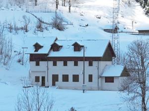 Un bâtiment blanc dans la neige avec de la neige dans l'établissement Centre de vacances Les Moulins, 