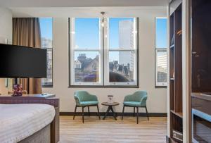 a hotel room with two chairs and a table and windows at Roomzzz Manchester Victoria in Manchester