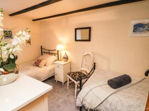 a bedroom with two beds and a chair at Black Gem Cottage in Whitby