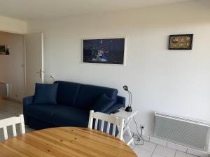 ein Wohnzimmer mit einem blauen Sofa und einem Tisch in der Unterkunft Cap sud vue panoramique sur mer et terre in Le Touquet-Paris-Plage
