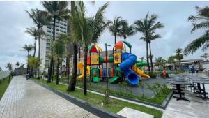 a playground with a slide in a park with palm trees at Salinas premium Resort in Salinópolis