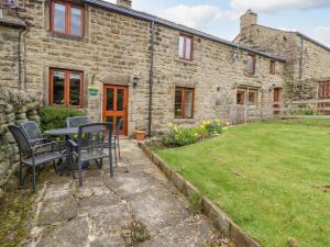 een stenen huis met een tafel en stoelen in de tuin bij Curlew Cottage in Keighley