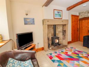a living room with a fireplace and a tv at Curlew Cottage in Keighley