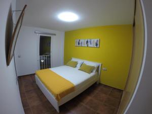 1 dormitorio con 1 cama con pared amarilla en Villa Sol, en Corralejo