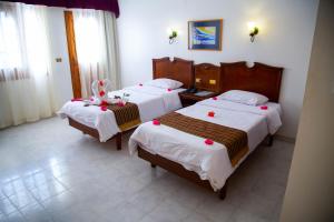 two beds in a hotel room with pink flowers on them at Happy Life Village Dahab in Dahab