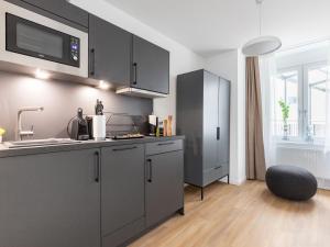 uma cozinha com armários cinzentos, um lavatório e uma cadeira em limehome Essen Kettwiger Straße em Essen