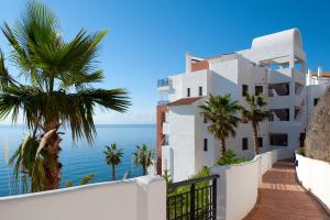 Un edificio blanco con palmeras y el océano. en Apartamento Vista mar frontal, en Torrox Costa