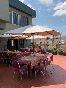 Un patio con mesas y sillas y una sombrilla. en Americana Hotel, en Cochabamba