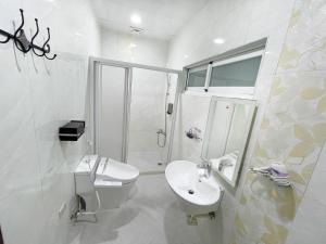 a white bathroom with a sink and a shower at Yi-Shiou Home in Taitung City
