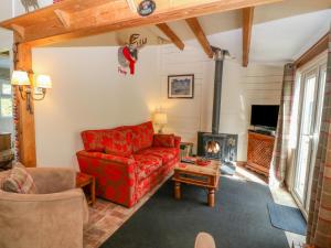 a living room with a red couch and a fireplace at Hafan Dawel in Caernarfon