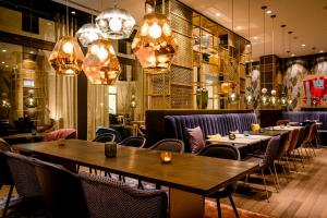 un restaurante con mesas, sillas y lámparas de araña en Motel One Aachen, en Aachen