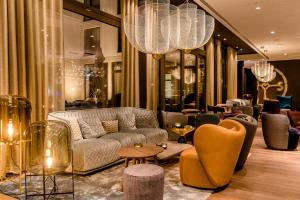 a lobby with a couch and chairs and chandeliers at Motel One Aachen in Aachen