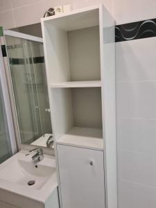 a white bathroom with a sink and a mirror at Appartement avec parking 50 m de la mer in De Panne