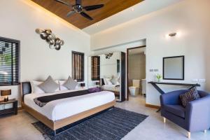 a bedroom with a king sized bed and a blue chair at Villa Crystal Two-bedroom private pool villa in Phuket +30 photos
