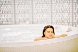 a woman is sitting in a bathtub at Hotel Sinaia in Sinaia