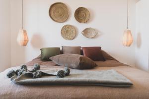 a bed with pillows and baskets on the wall at SwellHouse in Tamraght Ouzdar
