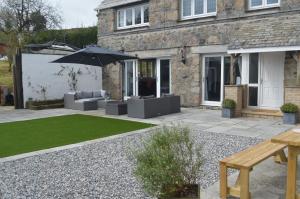 a patio with chairs and an umbrella and a lawn at The Cottage, Treliggon Farm in Lanivet