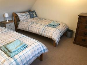 a bedroom with two beds and a dresser and a night stand at Kildinguie - Traditional Cottage - on NC 500 Route in Tongue