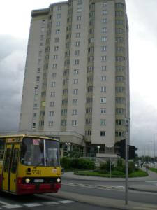 un bus jaune passant devant un grand bâtiment dans l'établissement Studio 6, à Varsovie