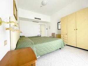 Un dormitorio con una cama verde y un escritorio de madera. en Hotel Reginella, en SantʼAgata sui Due Golfi