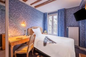 a bedroom with a desk and a bed and a table at Hôtel Baudelaire Opéra in Paris