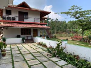 a house with a stone walkway in front of it at Creekside Cabin in Madikeri