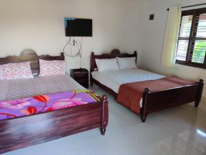 a bedroom with two beds and a flat screen tv at Creekside Cabin in Madikeri