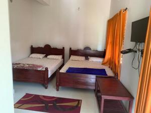 a bedroom with two beds and a tv in it at Creekside Cabin in Madikeri